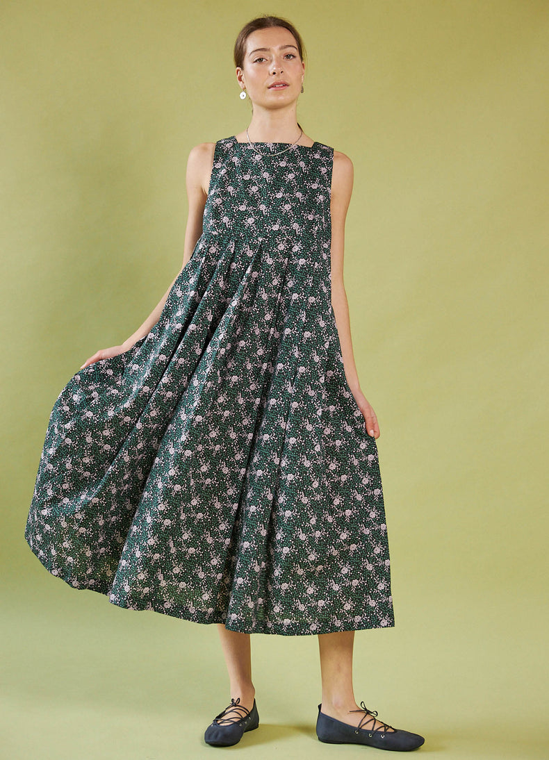 Woman wearing a Daylight Moon Liberty Print sleeveless floral dress against a green background
