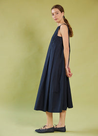 Woman wearing a Daylight Moon navy dress against a green background