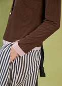 Daylight Moon Brown jacket with pink cuffs and a person wearing striped pants against a green background