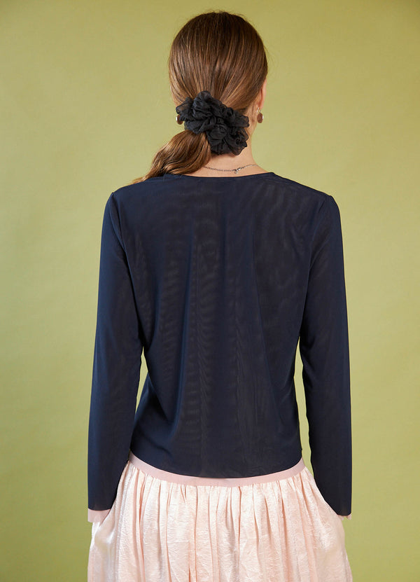 Person wearing a Daylight Moon navy long-sleeve top with a green background