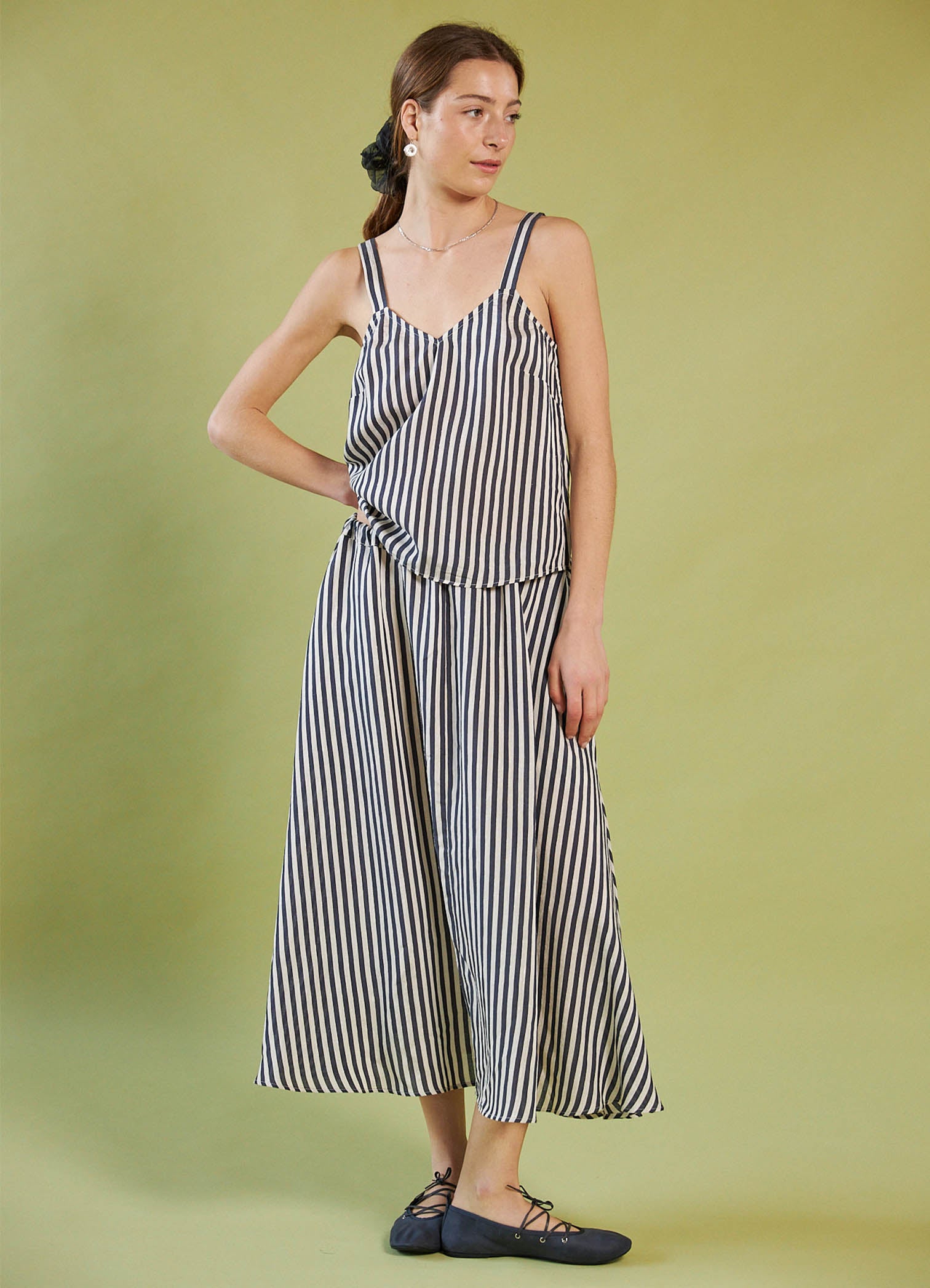 Woman wearing a Daylight Moon black and white striped dress against a green background